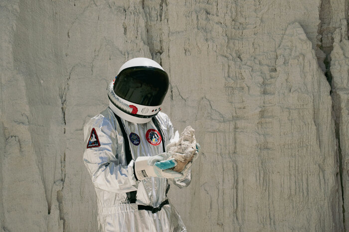 Analog astronaut in a white suit walking through a canyon
